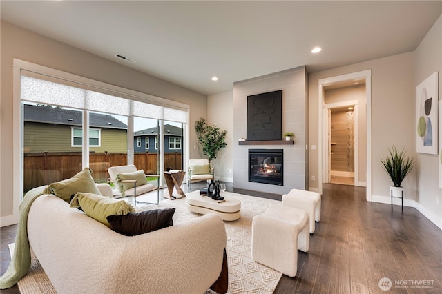 living area featuring visible vents, dark wood-type flooring, baseboards, recessed lighting, and a fireplace