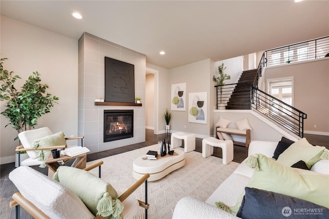 living area featuring stairway, wood finished floors, baseboards, recessed lighting, and a tile fireplace