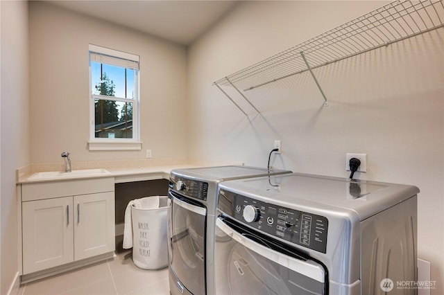 laundry room with cabinet space, light tile patterned floors, independent washer and dryer, and a sink