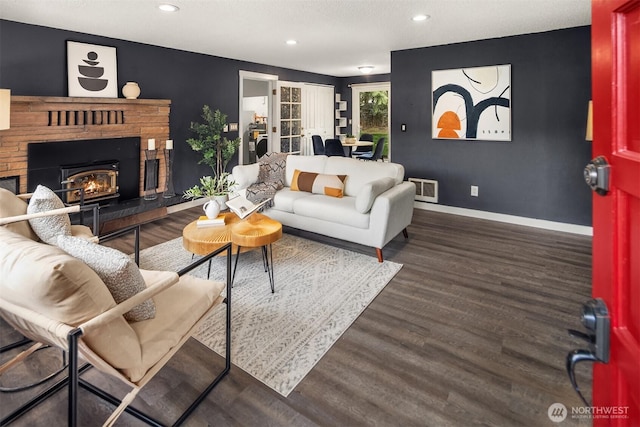 living area with visible vents, baseboards, recessed lighting, wood finished floors, and a glass covered fireplace