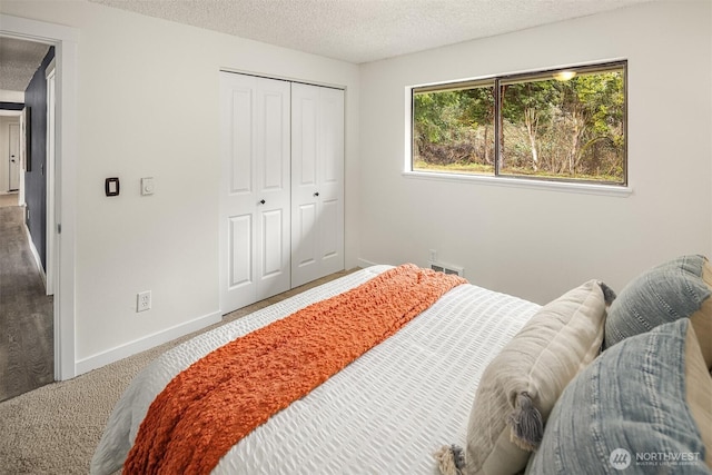 carpeted bedroom featuring baseboards, visible vents, a closet, and a textured ceiling