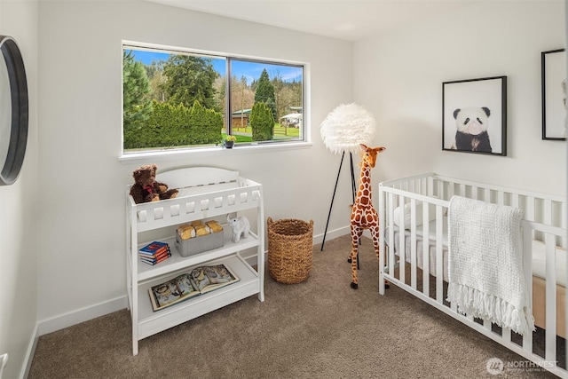 carpeted bedroom featuring a nursery area and baseboards