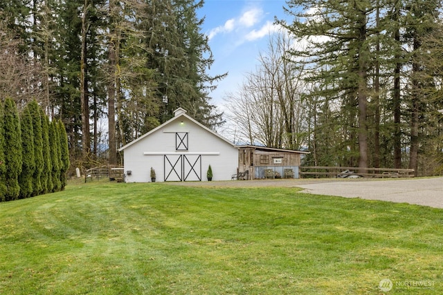 view of barn with a lawn and fence