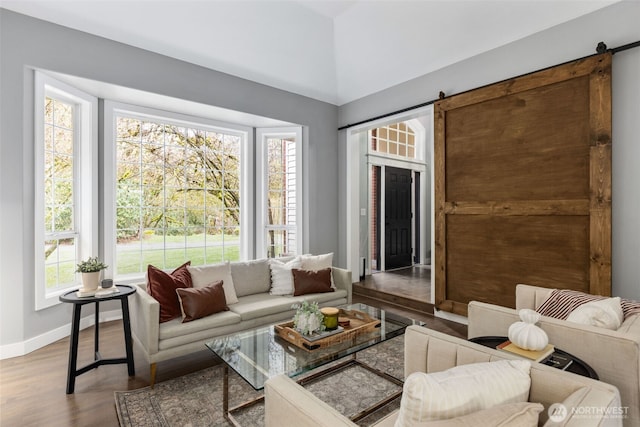 living room with a barn door, plenty of natural light, baseboards, and wood finished floors