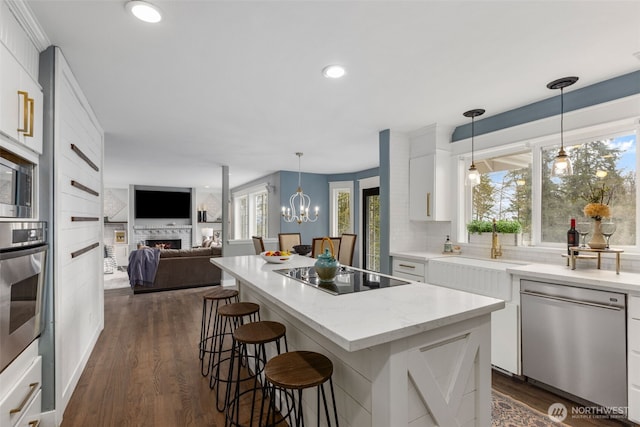 kitchen with a notable chandelier, white cabinets, appliances with stainless steel finishes, and a kitchen island