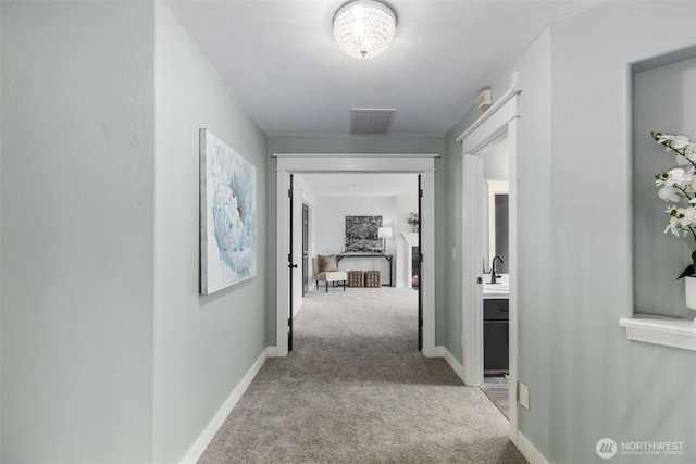 hall with visible vents, carpet floors, and baseboards