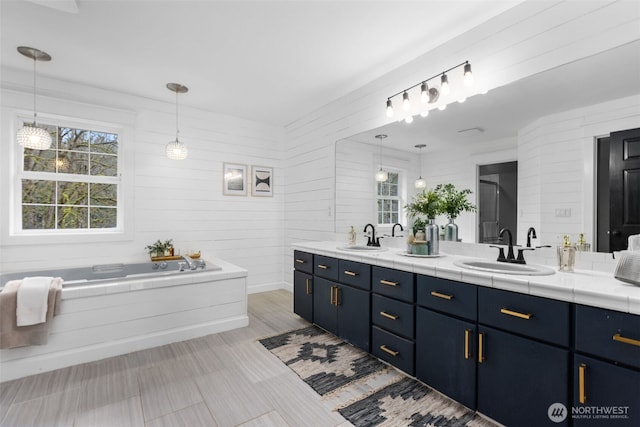 full bath featuring a sink, a garden tub, and double vanity