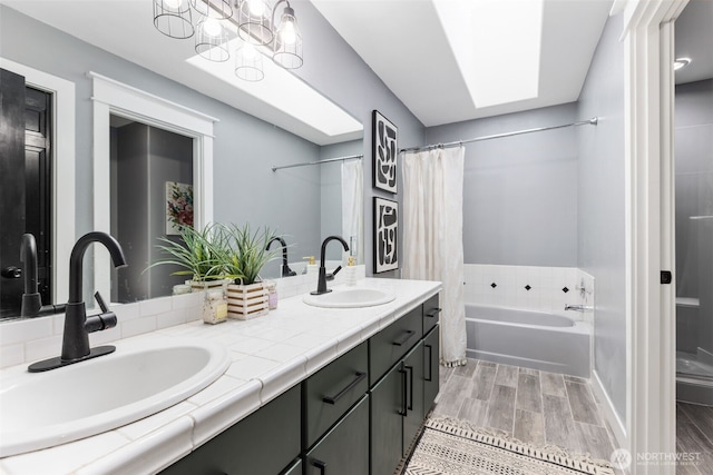 bathroom featuring a sink, wood finish floors, a skylight, and a bathing tub