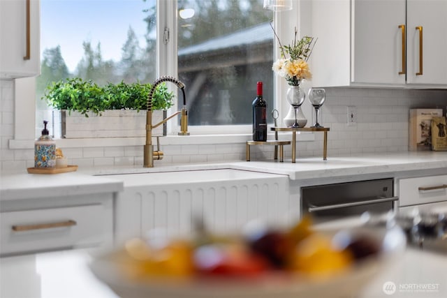 interior details with light stone counters, decorative backsplash, white cabinets, and a sink