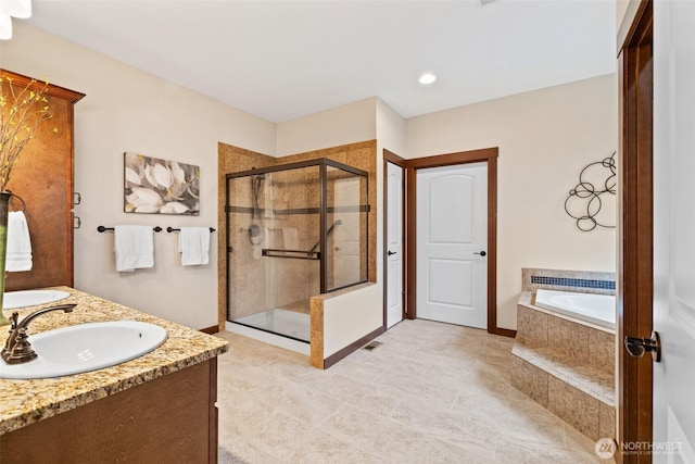 bathroom with visible vents, double vanity, a sink, a shower stall, and a garden tub