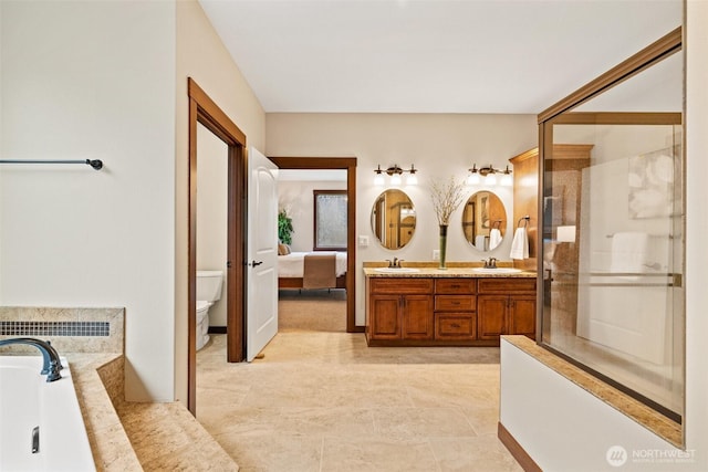 ensuite bathroom with a sink, toilet, double vanity, and a shower stall