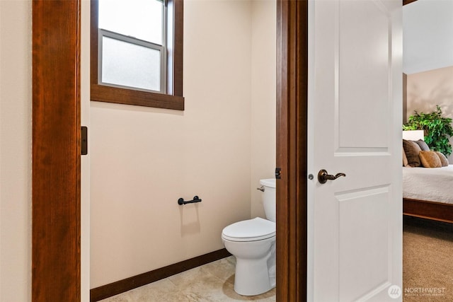 bathroom featuring tile patterned flooring, toilet, baseboards, and connected bathroom