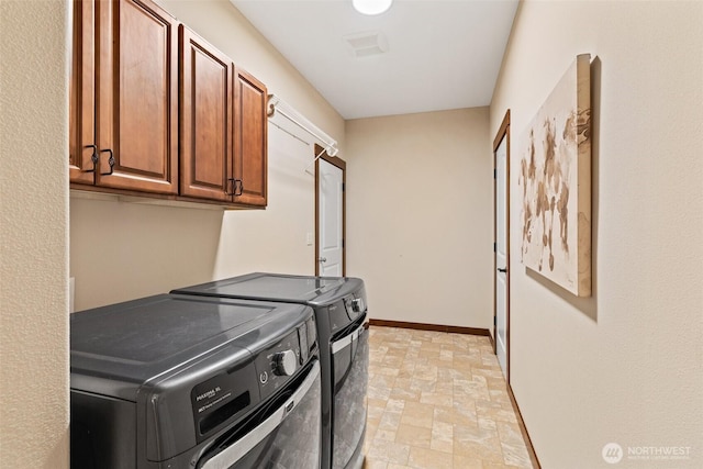 washroom with baseboards, stone finish flooring, cabinet space, and independent washer and dryer