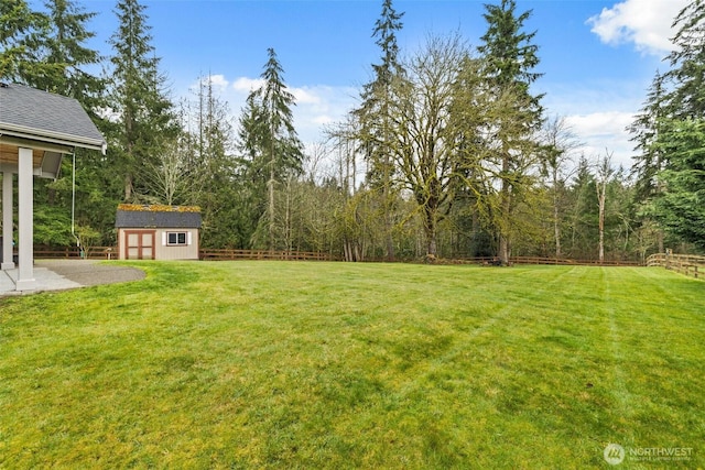 view of yard featuring a storage unit, a patio, an outbuilding, and fence