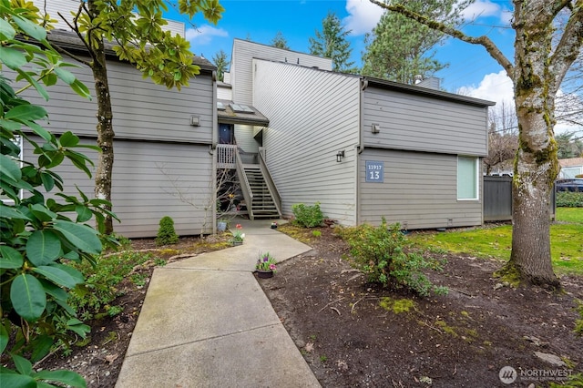 back of property featuring a chimney, stairs, and fence