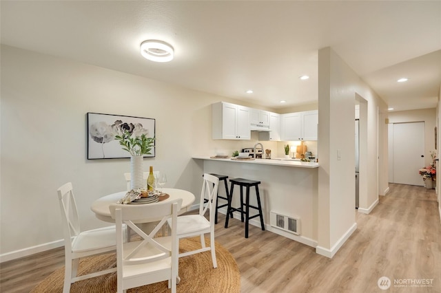 dining space featuring baseboards, visible vents, and light wood finished floors