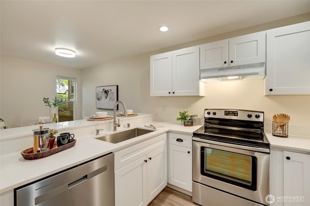 kitchen featuring under cabinet range hood, a sink, appliances with stainless steel finishes, white cabinets, and light countertops