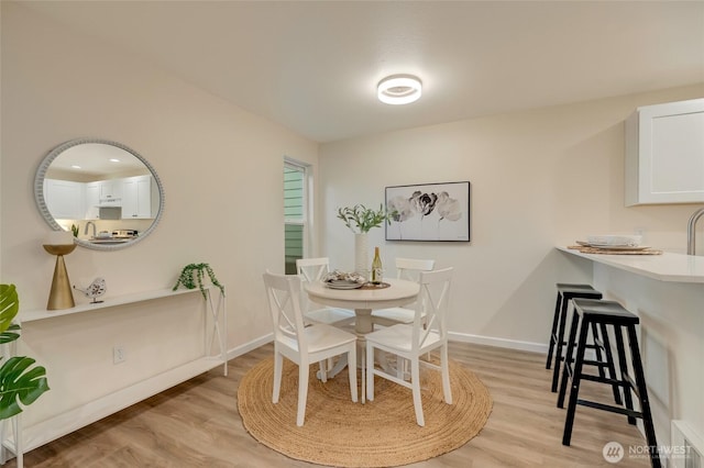 dining space with visible vents, baseboards, and light wood finished floors