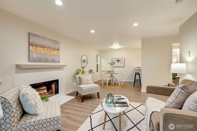 living room with a fireplace, recessed lighting, baseboards, and light wood finished floors