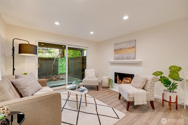 living area featuring recessed lighting, baseboards, wood finished floors, and a fireplace