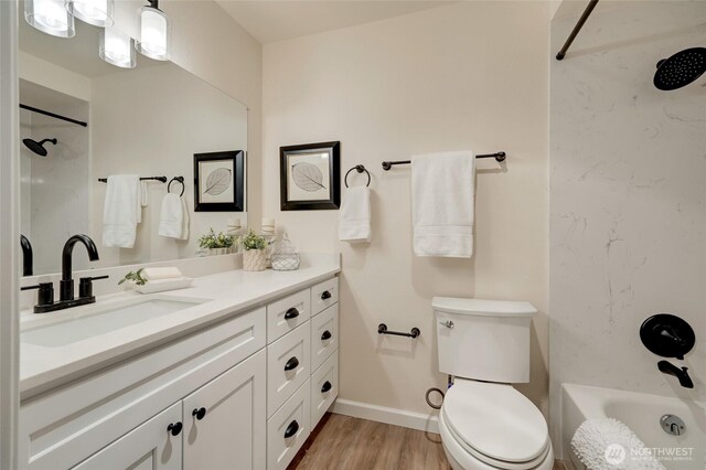 bathroom featuring vanity, toilet, wood finished floors, and baseboards