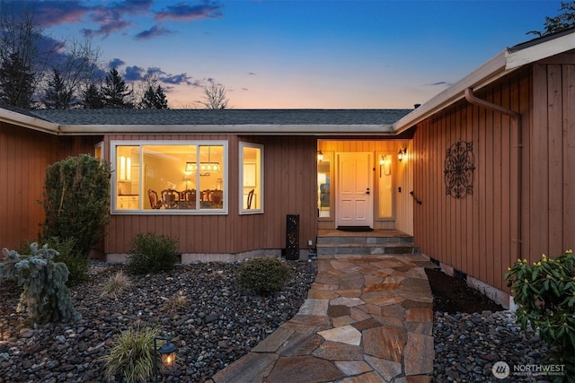 view of exterior entry with a shingled roof