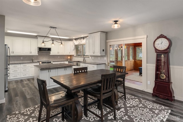 dining space featuring dark wood finished floors and a wainscoted wall