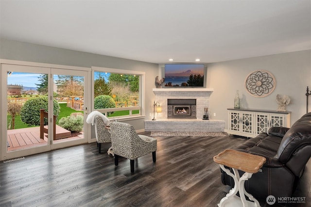 living room featuring wood finished floors, visible vents, baseboards, a fireplace, and recessed lighting