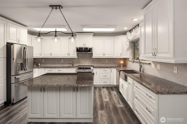 kitchen with backsplash, white cabinets, stainless steel appliances, and a sink