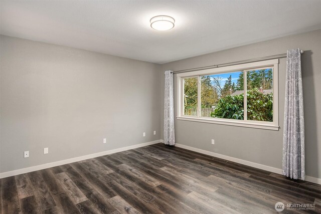 empty room featuring dark wood-type flooring and baseboards