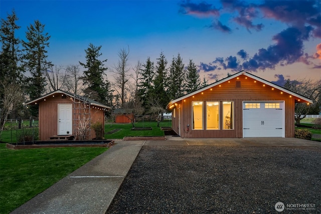 exterior space featuring gravel driveway, fence, a lawn, an outdoor structure, and a garage