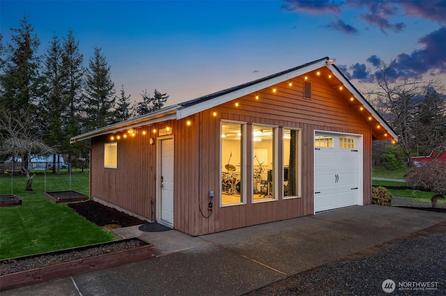 outdoor structure at dusk featuring a lawn and driveway