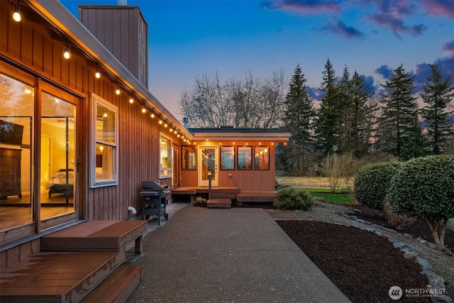 patio terrace at dusk featuring a grill and a deck