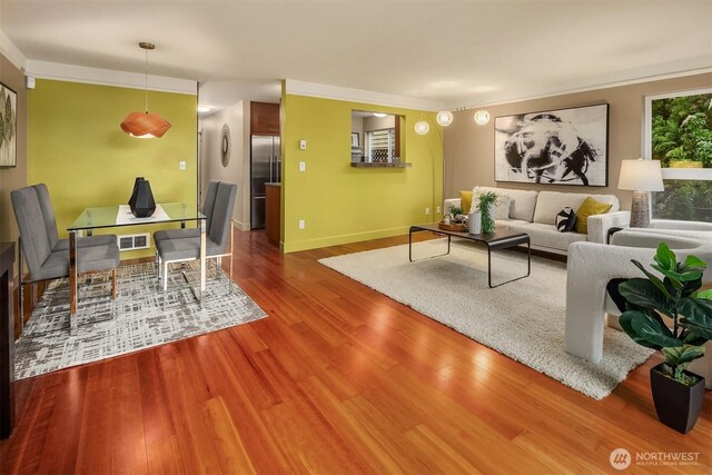 living area featuring visible vents, ornamental molding, and wood finished floors