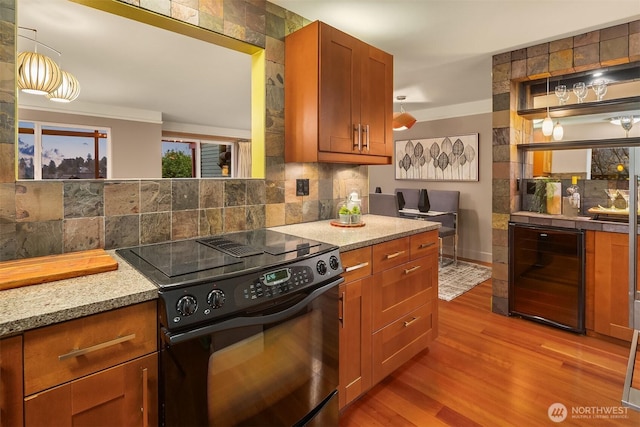 kitchen featuring beverage cooler, black electric range, tasteful backsplash, wood finished floors, and light stone countertops