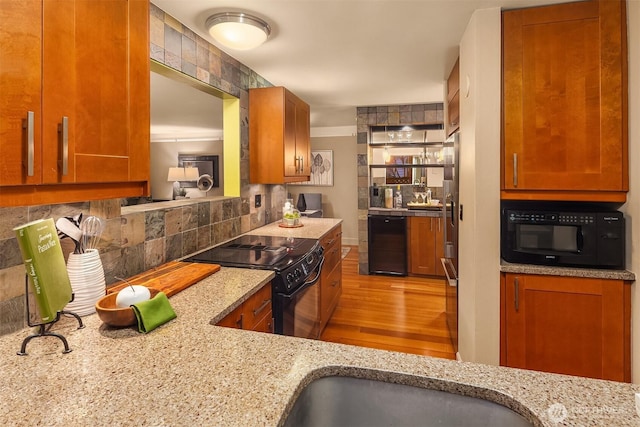 kitchen featuring light stone countertops, light wood finished floors, brown cabinets, black appliances, and tasteful backsplash