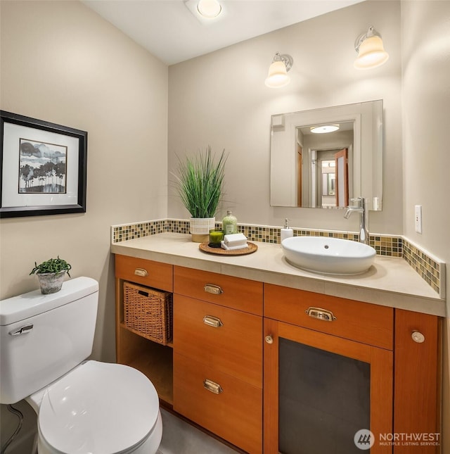 bathroom with vanity, toilet, and tasteful backsplash