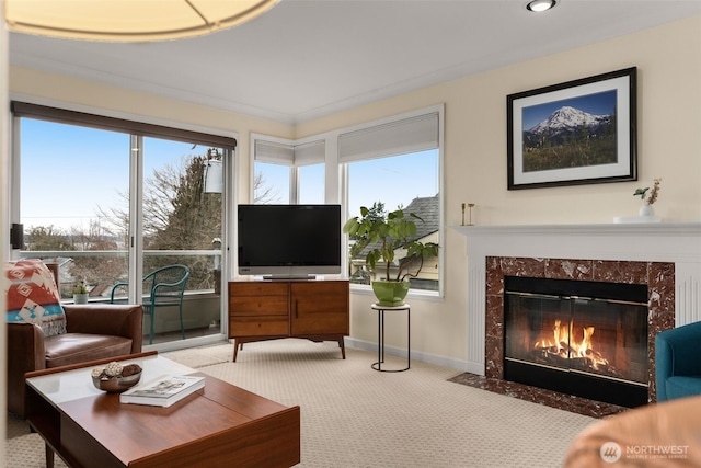 living area featuring a wealth of natural light, a premium fireplace, light carpet, and baseboards