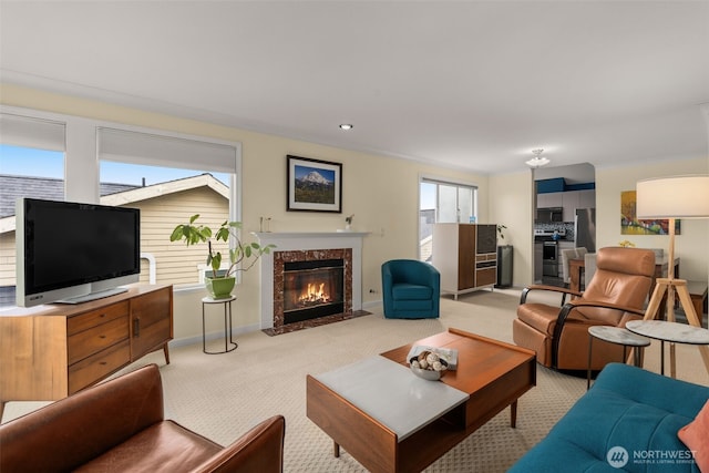 living room featuring recessed lighting, a fireplace, baseboards, and light carpet