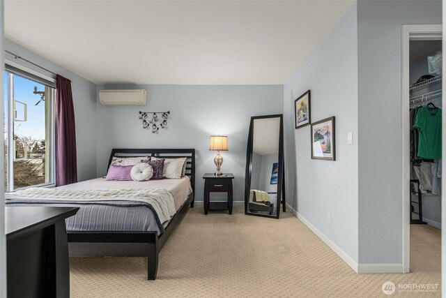 bedroom featuring a walk in closet, baseboards, an AC wall unit, carpet floors, and a closet