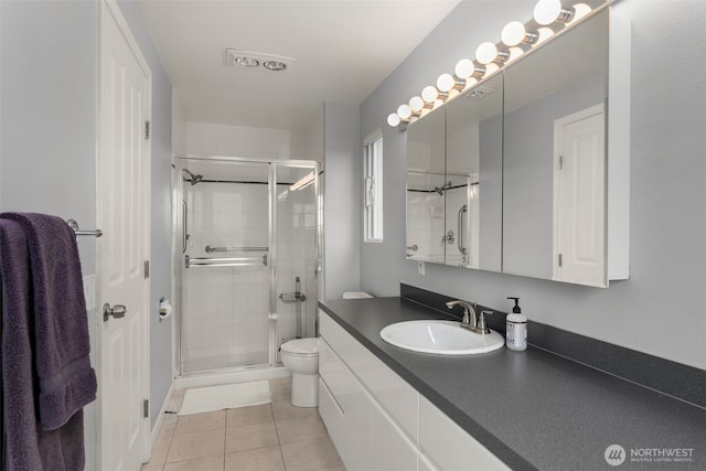 bathroom with toilet, a stall shower, vanity, and tile patterned flooring