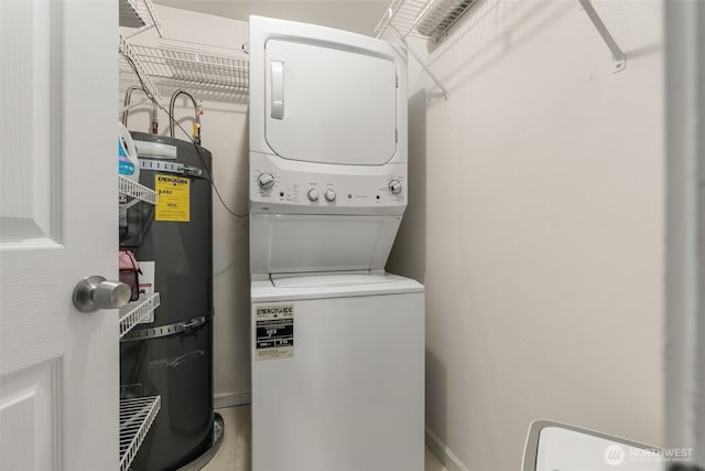 washroom with stacked washer / dryer, baseboards, laundry area, and water heater