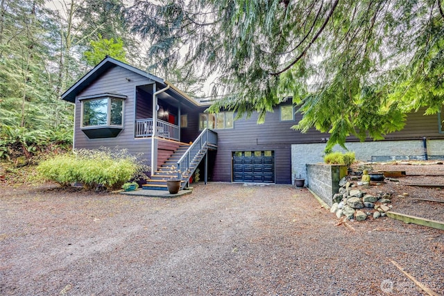 view of front facade featuring stairway, a porch, driveway, and a garage