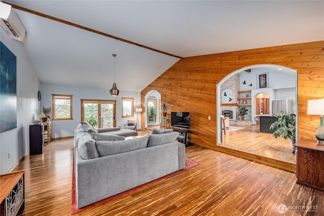 living area featuring arched walkways, wooden walls, and a wall mounted AC