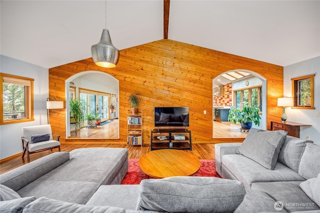 living room featuring vaulted ceiling, wooden walls, and wood finished floors