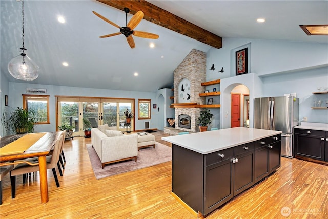 kitchen featuring open shelves, light countertops, arched walkways, and freestanding refrigerator