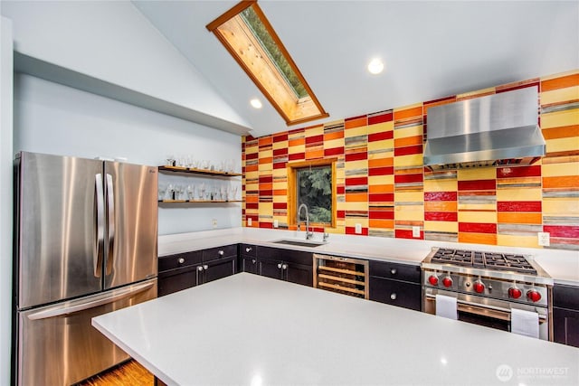 kitchen with a sink, open shelves, wine cooler, appliances with stainless steel finishes, and wall chimney range hood