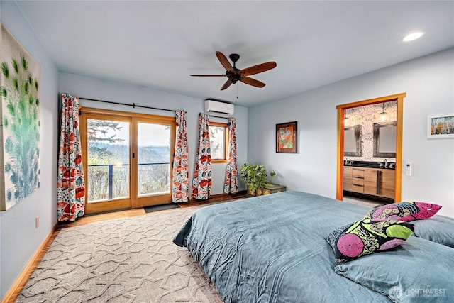 bedroom featuring an AC wall unit, ensuite bathroom, wood finished floors, recessed lighting, and access to exterior