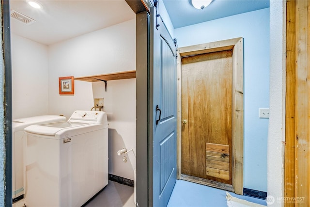 laundry area featuring visible vents, baseboards, a barn door, laundry area, and separate washer and dryer