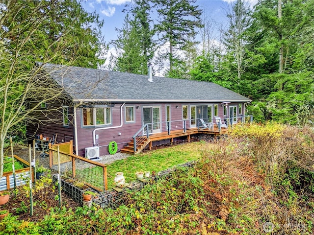 back of property with a deck, a vegetable garden, and roof with shingles